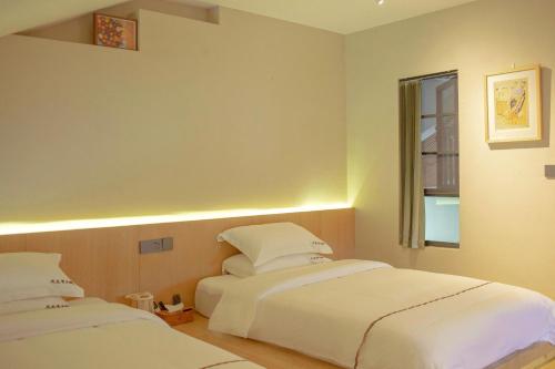 a bedroom with two beds and a window at Phoenix Dragon M.I.C.E Hotel in Kunming