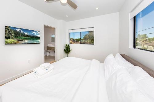Un dormitorio blanco con una cama grande y dos ventanas. en Modern 2BR Back House w/ TVs & Full Kitchen, en Los Ángeles