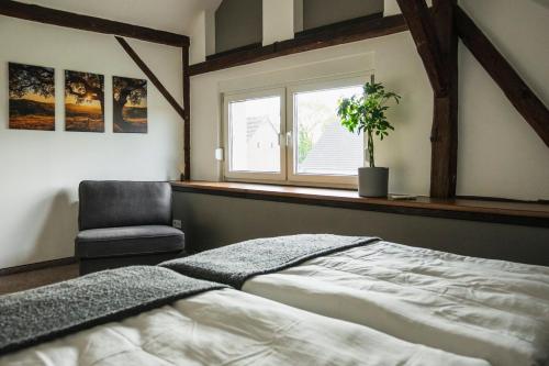 a bedroom with a bed and a chair and a window at Ferienhaus zum Johannisthal in Hosena