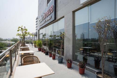a balcony of a restaurant with tables and potted plants at AR Suites KLJ Square in Gurgaon