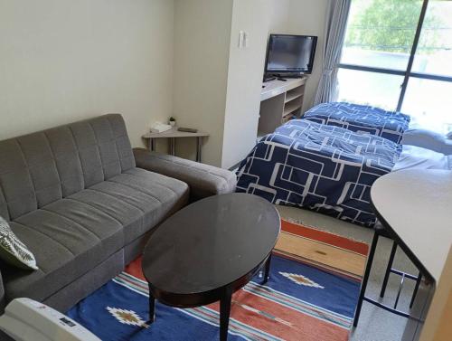 a living room with a couch and a bed at フューデイズコンドミニアム定山渓206号室 in Jozankei