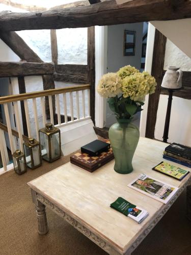 a table with a vase of flowers on it at Logaston Common Farmhouse in Woonton