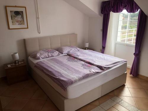 a bedroom with a bed with purple sheets and a window at Villa Anna in Savudrija