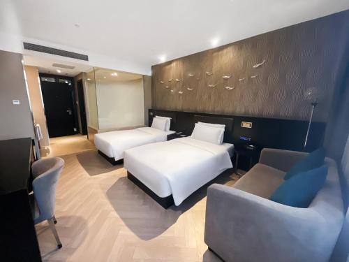 a hotel room with two beds and a chair at Crystal Orange Hotel Shanghai International Tourism Resort Chuansha in Shanghai