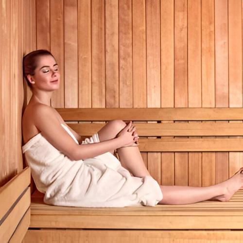 a woman is sitting in a sauna at Hotel Nettunia in Rimini