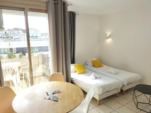 Cette chambre comprend 2 lits, une table et un balcon. dans l'établissement Résidence Graziella studio 605, à Juan-les-Pins