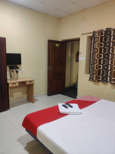 a room with a bed and a desk and a television at Hotel O Chez Pondy in Kottakupam
