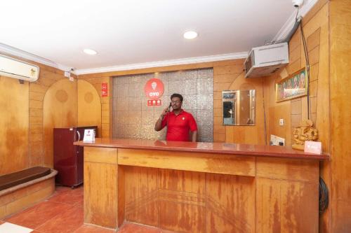 a man standing at a bar talking on a cell phone at Hotel O Chez Pondy in Kottakupam