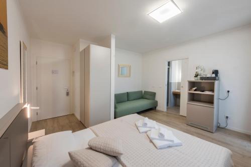 a white room with a bed and a green couch at Guesthouse Stadio in Lignano Sabbiadoro