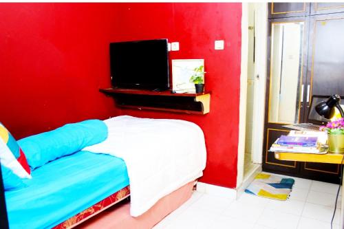 a red room with a bed and a tv at Lagura Residence in Jakarta