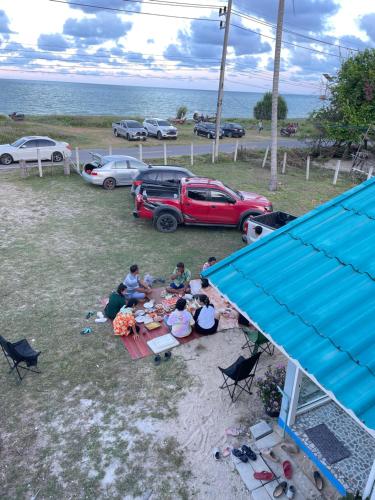 a group of people sitting at a picnic table near the ocean at Earnhomestay sichon in Ban Plai Thon