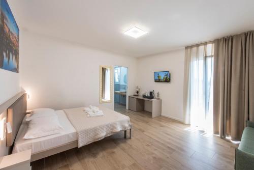 a white bedroom with a bed and a window at Guesthouse Stadio in Lignano Sabbiadoro
