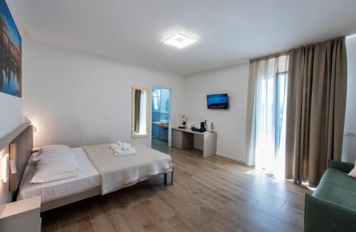 a white bedroom with a bed and a couch at Guesthouse Stadio in Lignano Sabbiadoro