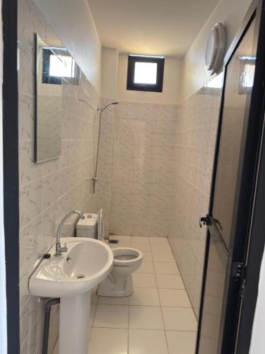 a white bathroom with a sink and a toilet at Sali- Laye Diass in Darou Rhamane