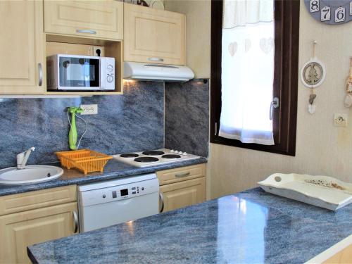 une cuisine avec un évier et une cuisinière four supérieur dans l'établissement Appartement cosy à Risoul 1850 : 2 pièces, coin montagne, 6 couchages, ski aux pieds, terrasse sud - FR-1-330-125, à Risoul