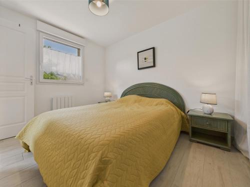 - une chambre avec un lit doté d'une couverture jaune et d'une fenêtre dans l'établissement Maisonnette 4 personnes - 300m de la plage, à Penvénan