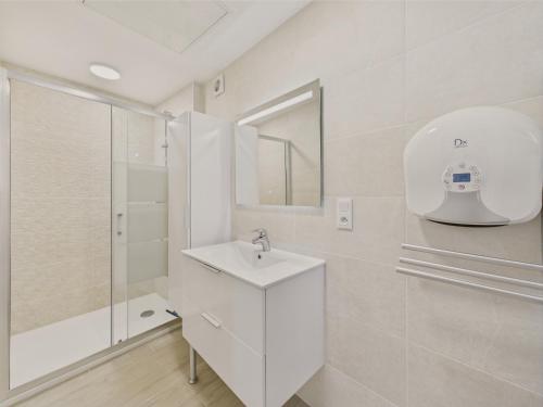 une salle de bain blanche avec un lavabo et une douche dans l'établissement Maisonnette 4 personnes - 300m de la plage, à Penvénan