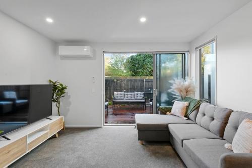 a living room with a couch and a tv at Cosy Oasis Close To CBD in Christchurch