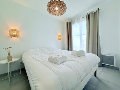 un lit blanc dans une chambre avec une fenêtre dans l'établissement La Brise des îles, à Yves