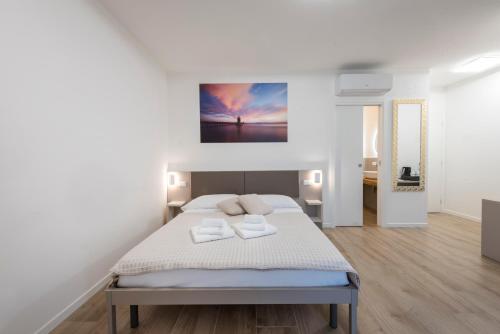 a white bedroom with a bed with two towels on it at Guesthouse Stadio in Lignano Sabbiadoro