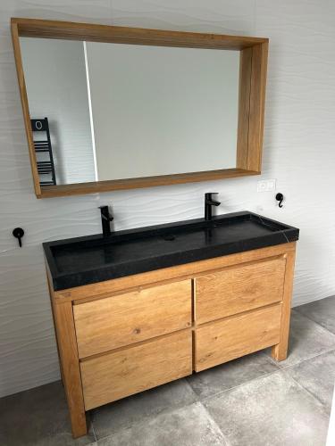 un lavabo de salle de bain avec un miroir et une commode en bois dans l'établissement Maison d'architecte à Morgat, à Crozon