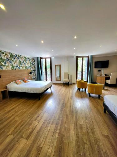 a large room with two beds and a television at Le Grand Hôtel Molière in Pézenas