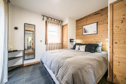 une chambre avec un grand lit avec un mur en bois dans l'établissement Echo du Pleney B004, à Morzine