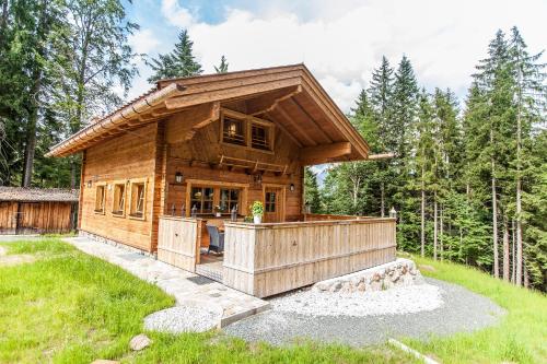 a log cabin in the woods with a wrap around deck at Chalet Haberlhütte in Fieberbrunn