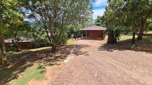 a brick walkway in a park with trees and a building at Robin Cottage Da Gama Lake in White River