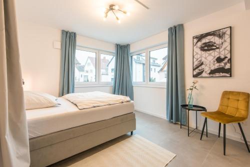 a bedroom with a bed and a chair and windows at Studio Bergstrasse 2 PAX NEU Parkplatz in Heppenheim an der Bergstrasse