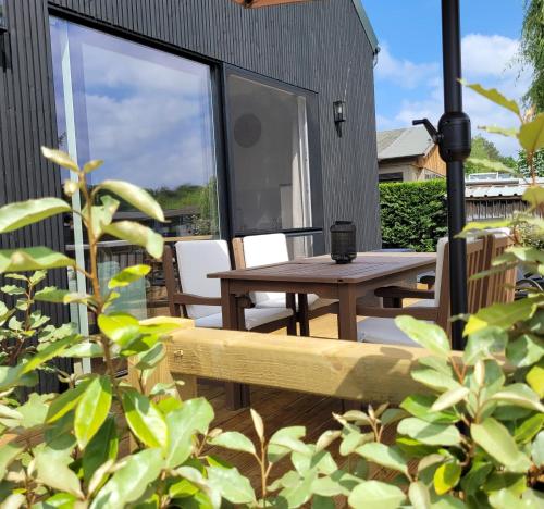 a patio with a wooden table and chairs and a window at Vakantiewoning aan het water, vissen, wandelen en genieten in de natuur in Geel