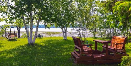 two chairs and a table in a yard with a swing at Condo 2 - Bord de l'eau SPA Barbecue & Foyer in Sainte-Anne-de-Beaupré