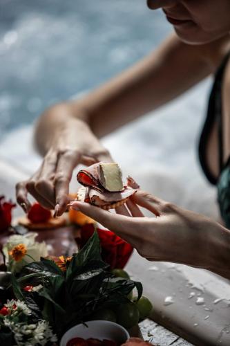 a woman is holding a sandwich on a table at Thulamela Couples Retreat in Hazyview