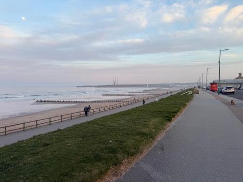 a beach with a fence and a road and the ocean at Ferryhills Riverside Retreat in Aberdeen