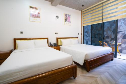 a bedroom with two beds and a large window at Phuc Hai Hotel Da Lat in Da Lat