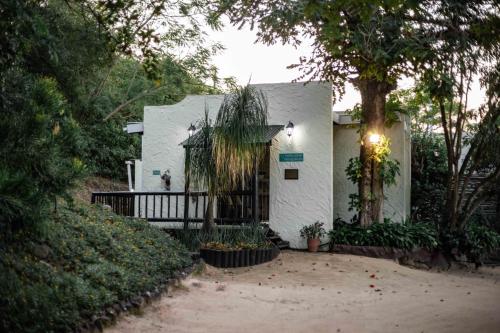 a white house with a porch and a tree at Thulamela Couples Retreat in Hazyview