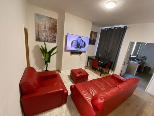 a living room with a red leather couch and a television at Cosy 2-Bed House - Sleeps 5 Garden & Pet-Friendly in Leicester