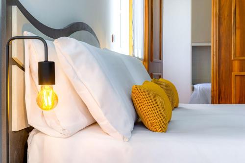 Una cama con almohadas blancas y una lámpara. en I Barcaioli, en Giardini Naxos