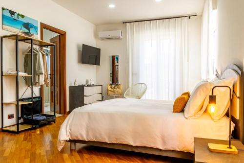 Un dormitorio con una gran cama blanca y un televisor. en I Barcaioli, en Giardini Naxos