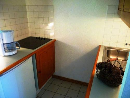 une petite cuisine avec un évier et une cuisinière dans l'établissement Appartement skis aux pieds, 4 couchages, balcon, wifi inclus - FR-1-513-66, à Courchevel