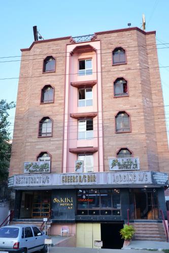 a brick building with a car parked in front of it at Sakthi Hotel in Pollāchi