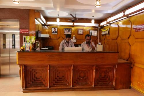 two men standing at a bar in a restaurant at Sakthi Hotel in Pollāchi