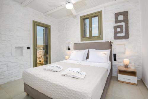 a white bedroom with a bed with towels on it at Onos Luxury Villas Kythnos in Kithnos