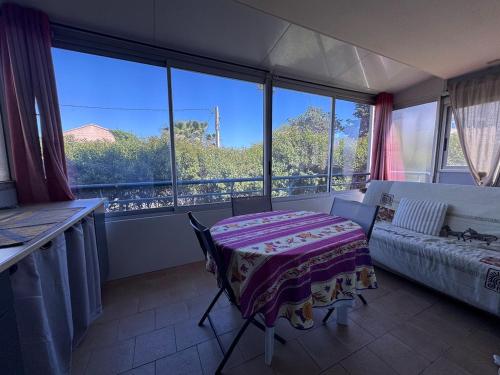 Habitación con mesa, sofá y ventanas. en L'endroit, en La Seyne-sur-Mer