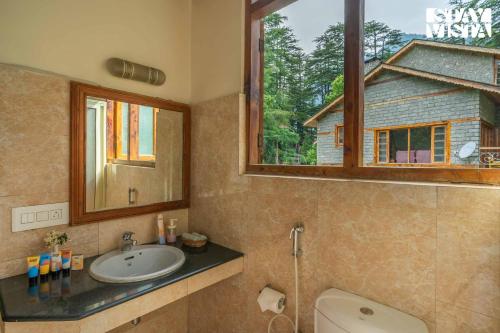 ein Bad mit einem Waschbecken, einem Fenster und einem WC in der Unterkunft StayVista at Retreat Cottages with Lawn, Bonfire in Manali