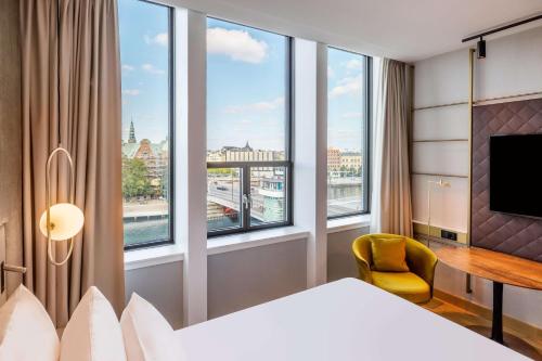 a hotel room with a bed and a desk and windows at NH Collection Copenhagen in Copenhagen