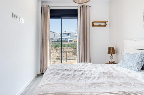 a white bedroom with a bed and a window at Izabell in Finestrat