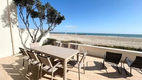 - une table et des chaises sur une terrasse donnant sur la plage dans l'établissement Réf 2152 - T5 en rez-de-plage, à Palavas-les-Flots