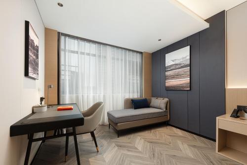 a living room with a couch and a chair and a desk at Atour X Hotel Chengdu Jinhua Wanda Zhonggang Plaza in Chengdu