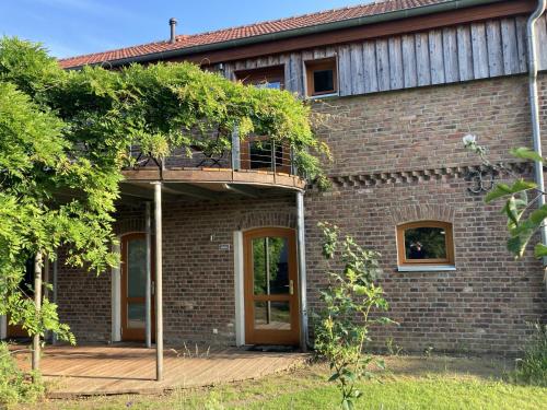 a brick house with a balcony and two doors at Dreigärten Brodowin in Brodowin